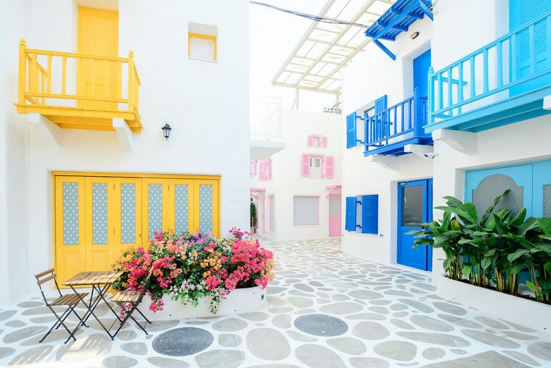 White walls surrounding a courtyard with doors and porches in bright yellow, pink, blue, and aqua
