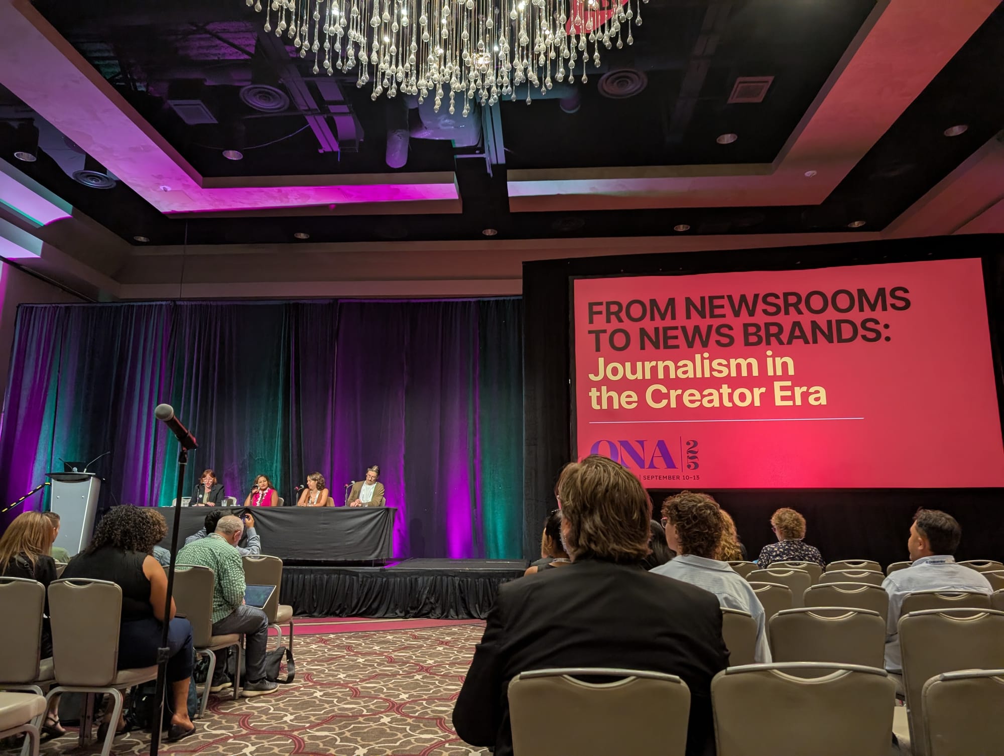 A photo taken from the audience of a panel discussion titled "From Newsrooms to News Brands: Journalism in the Creator Era"